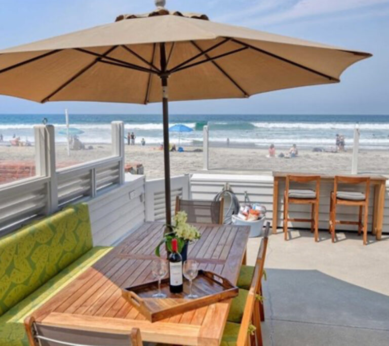 Beach front deck with an umbrella and table.